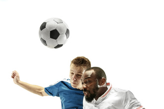 Das Bild zeigt zwei Männer, die in die Luft springen, um einen Kopfball beim Fußball auszuführen.